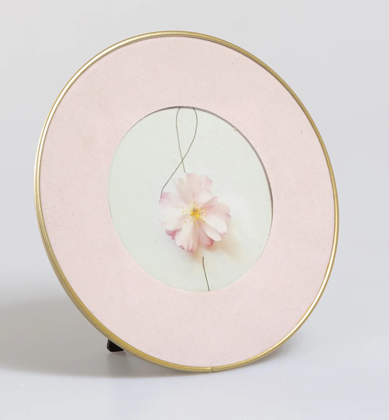 Pink round photo frame with gold rim and pressed flower